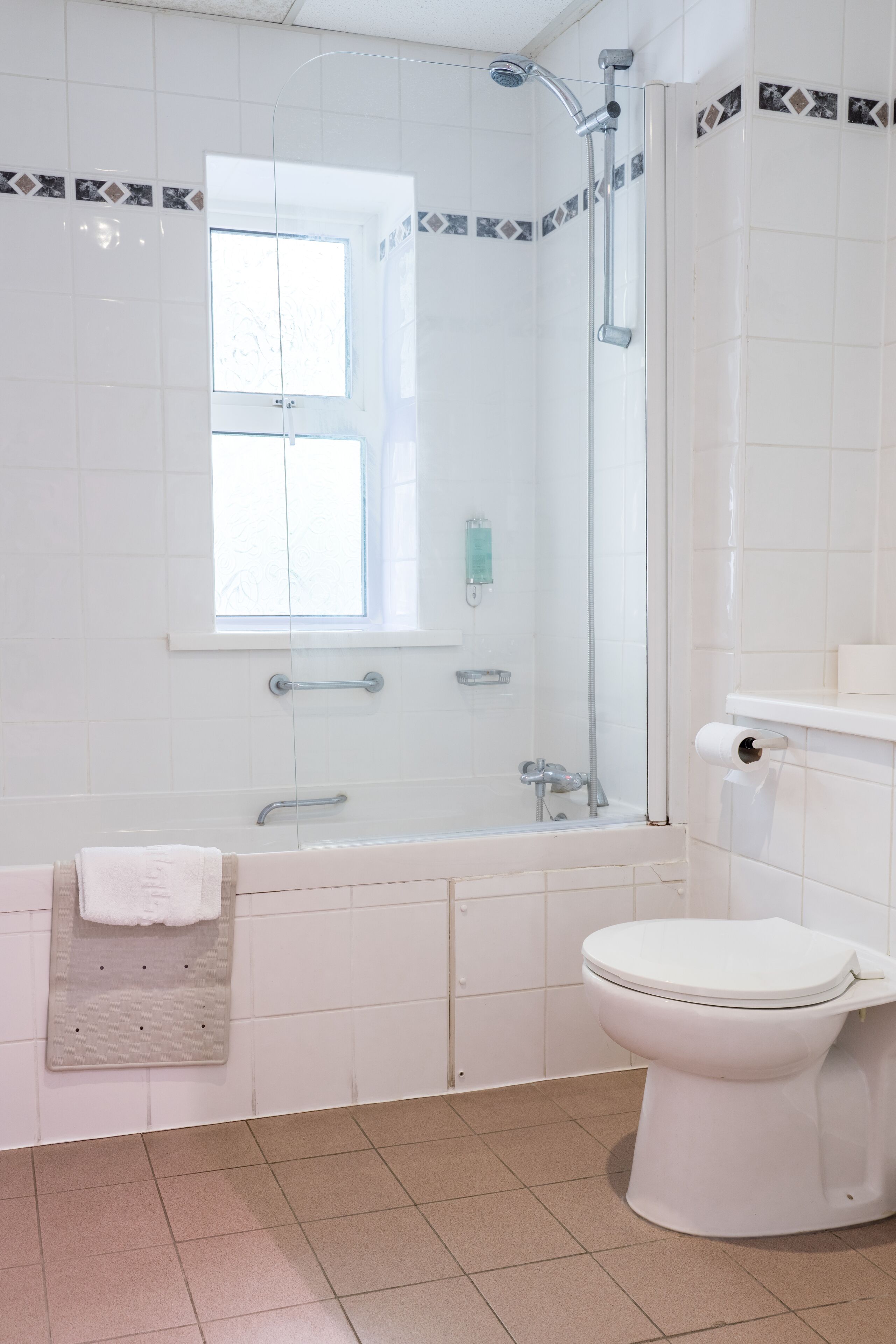 Ein Badezimmer mit Badewanne, Toilette und einem Fenster.
