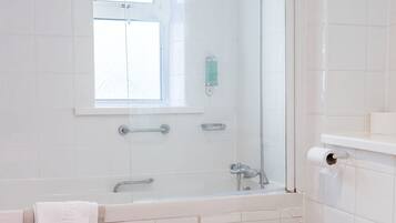 Un baño con bañera, inodoro y ventana.