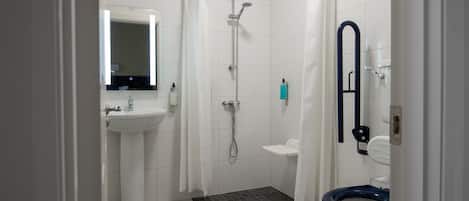 A bathroom with a shower, toilet, sink, and a mirror.