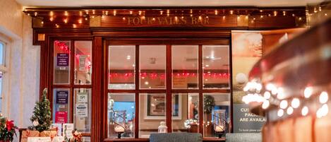 A bar with a Christmas tree and seating area.