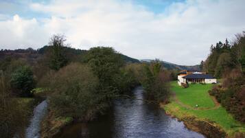 A house with a large lawn and a river in the foreground.