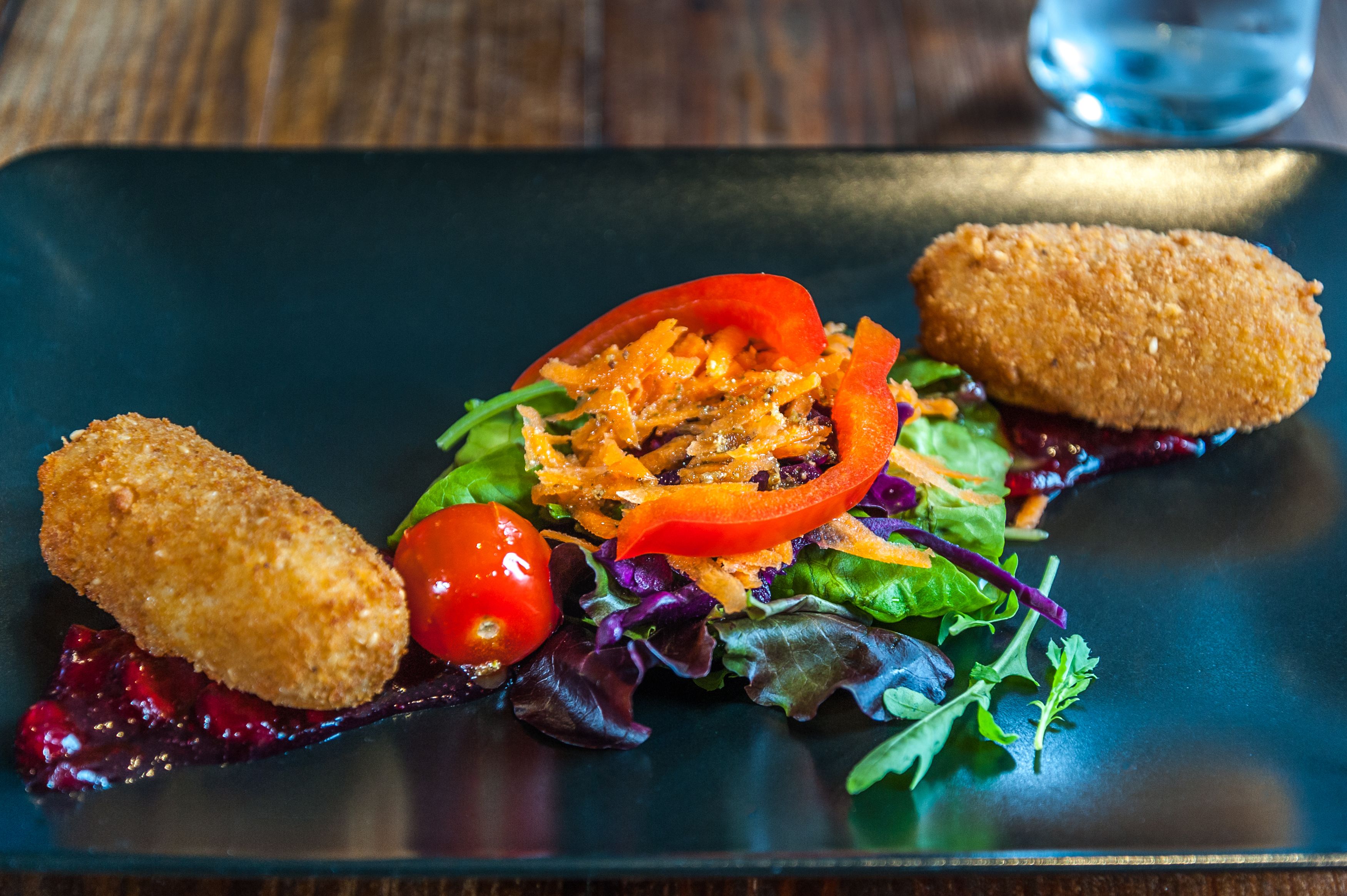 A plated dish with two breaded items and a salad.