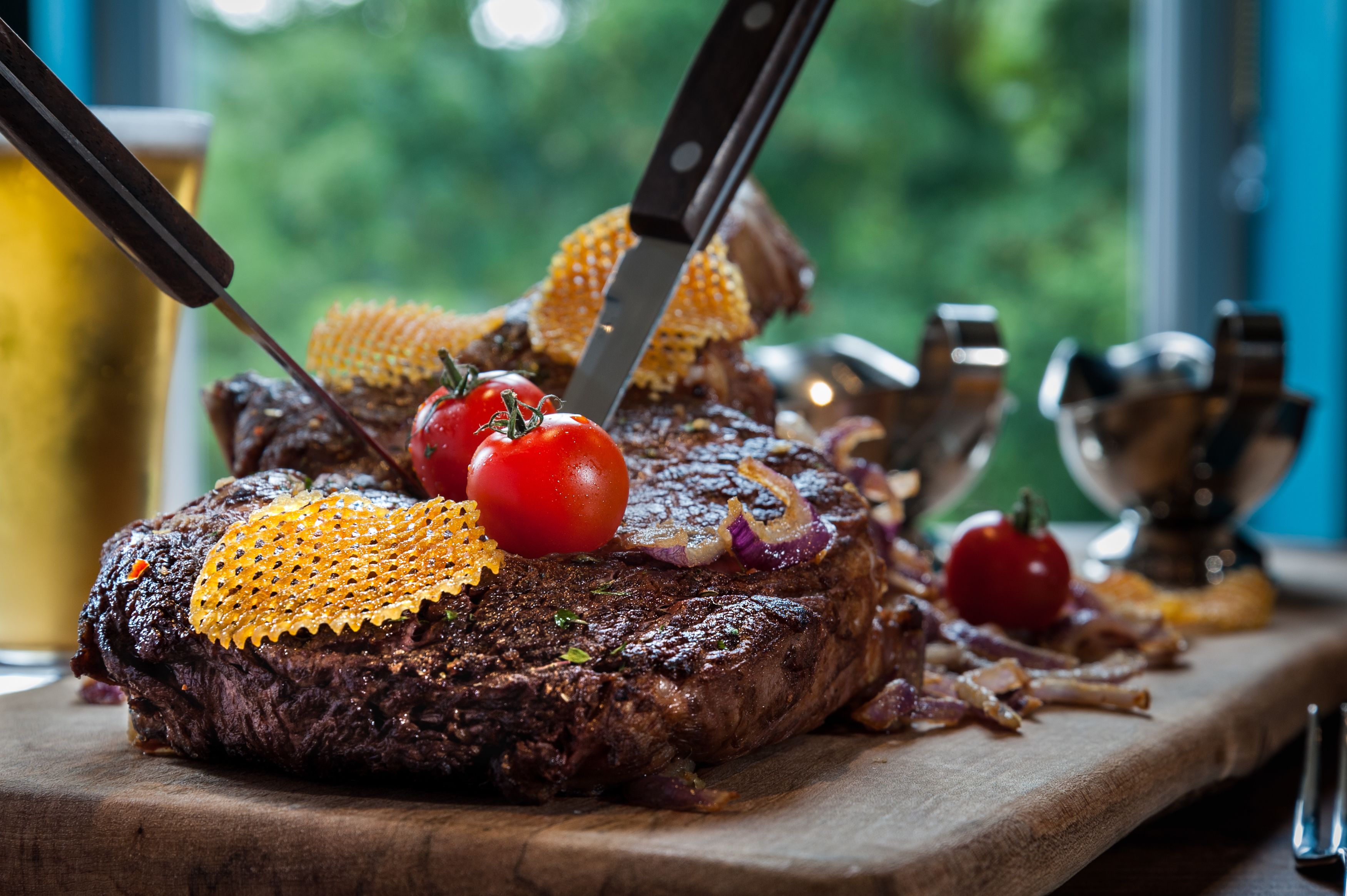A steak with a knife and fork on a wooden board.