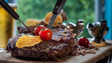 A steak with a knife and fork on a wooden board.