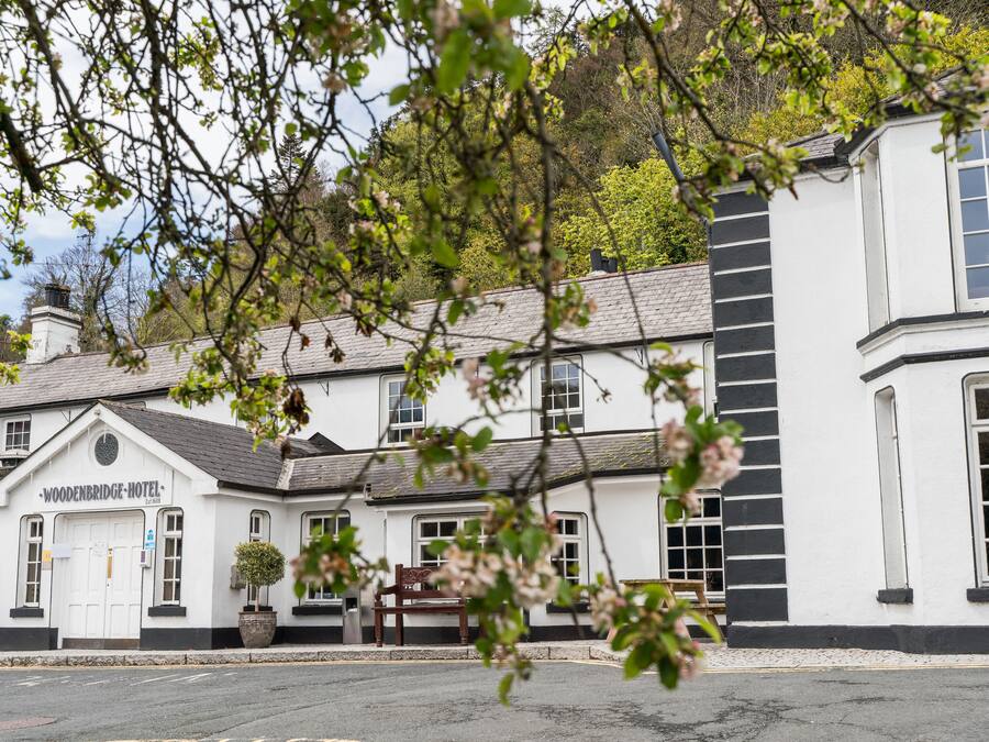 A traditional white building with a sign reading "Woodenbridge Hotel."