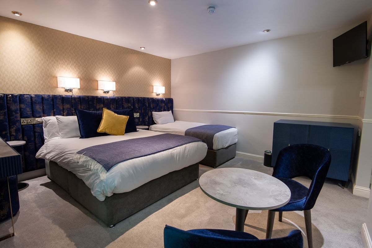 A hotel room with two beds, a round table, and a TV mounted on the wall.