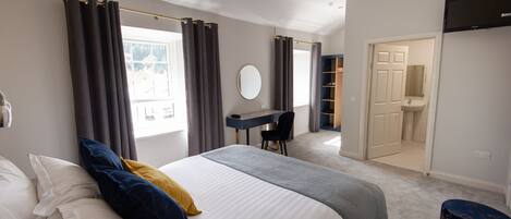 Un dormitorio con cama, escritorio y vestidor.