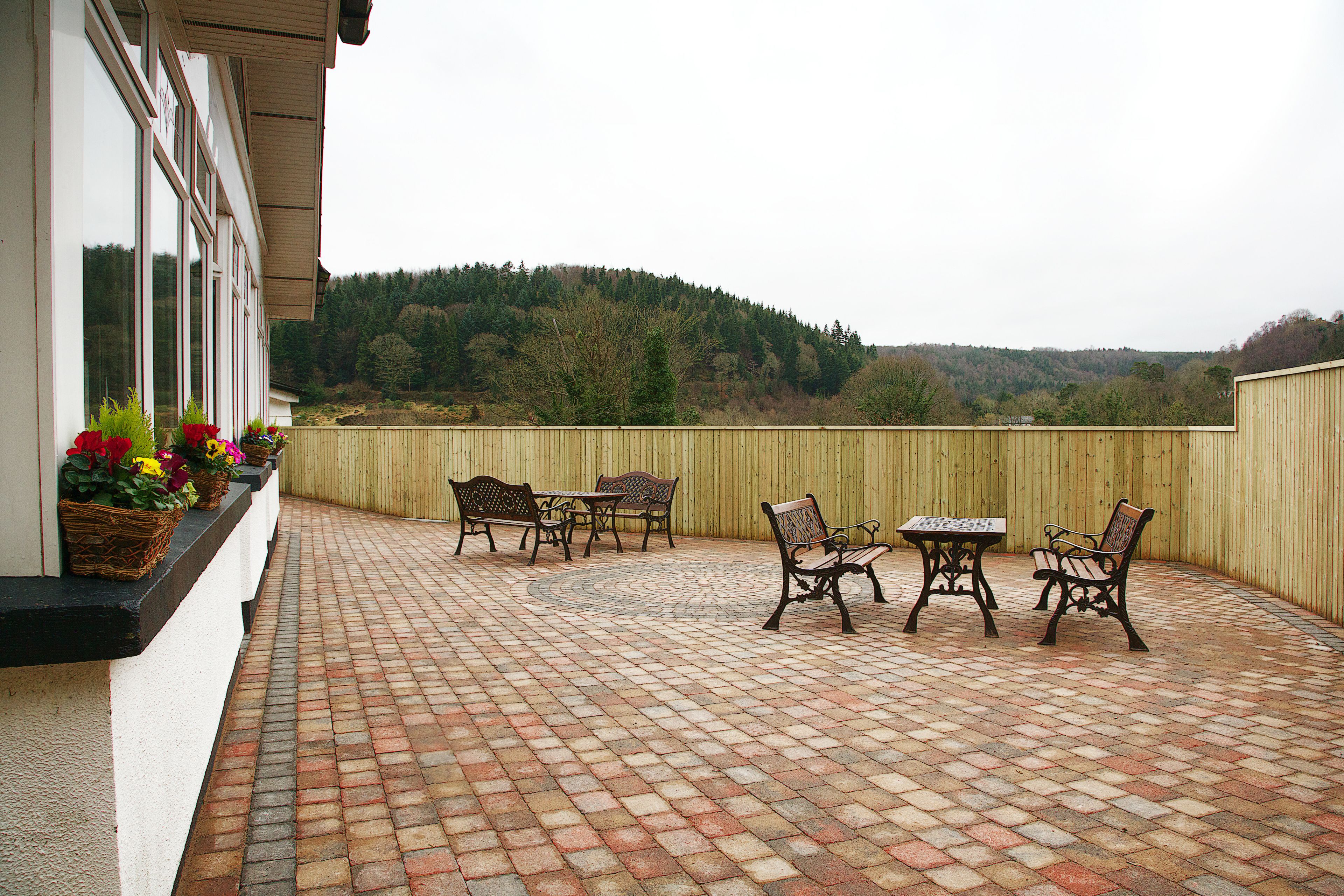 A patio with brick flooring, outdoor furniture, and a view of a forested hill.