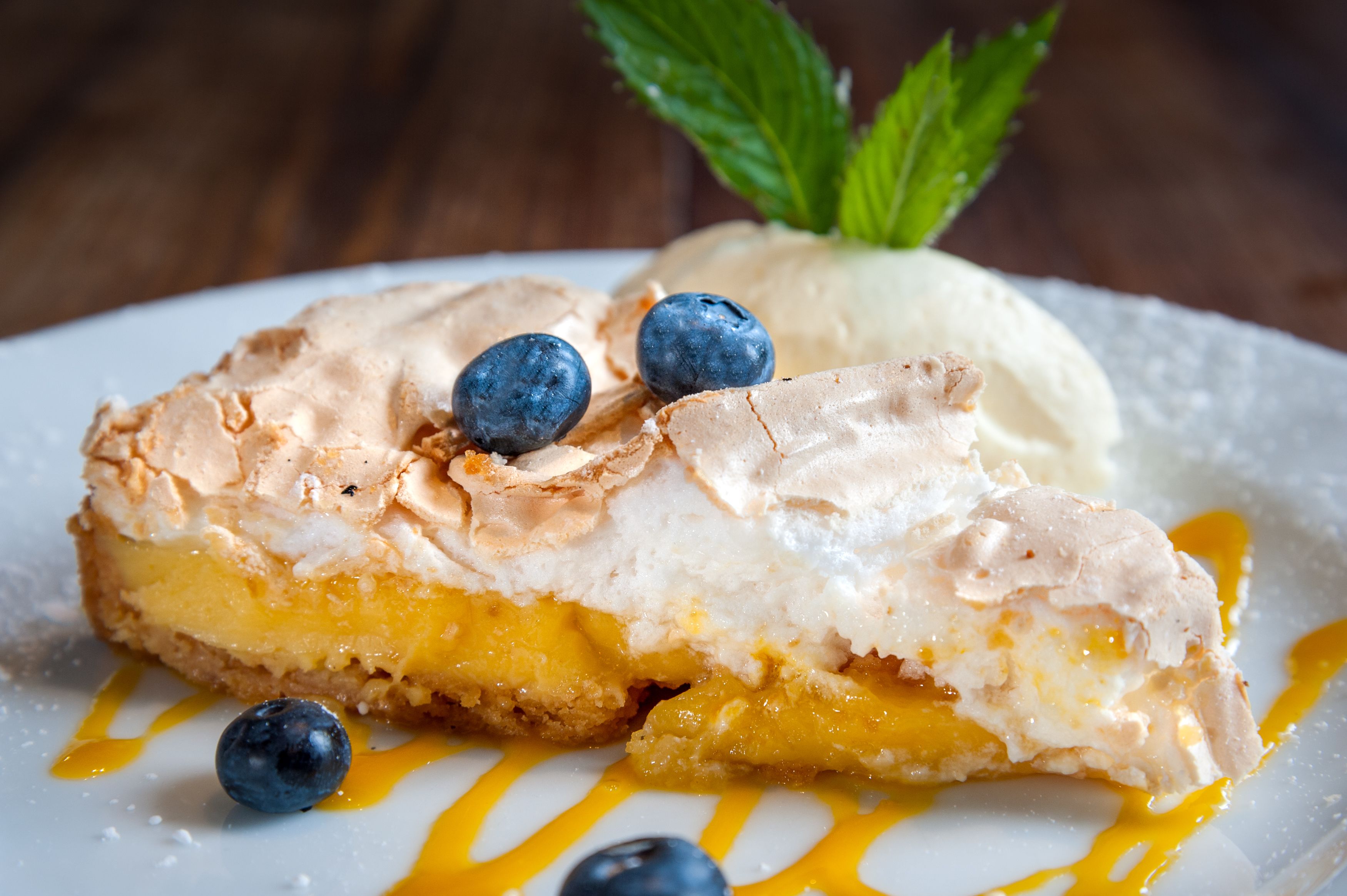 A dessert with meringue, blueberries, and a mint garnish on a plate.