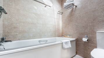 Une salle de bain moderne équipée d’une baignoire, de toilettes et d’un espace douche.