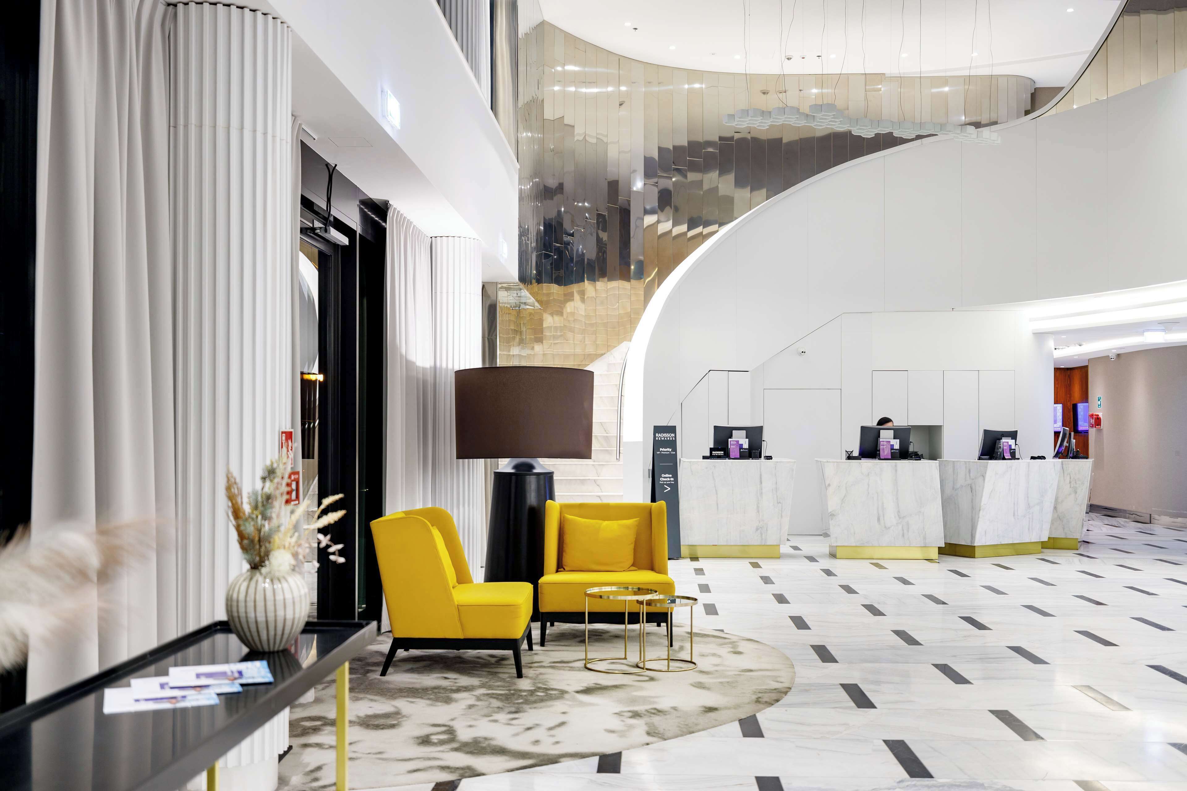 Eine moderne Hotelhalle mit Empfangstresen, Sitzgelegenheiten und einer Treppe.