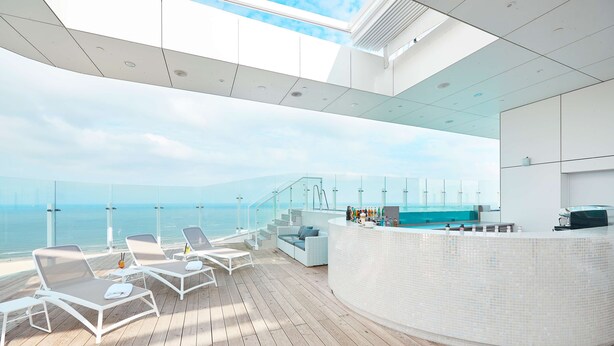 Ein moderner Außenbereich mit Lounge-Möbeln, einer Bar und Blick auf den Ozean.