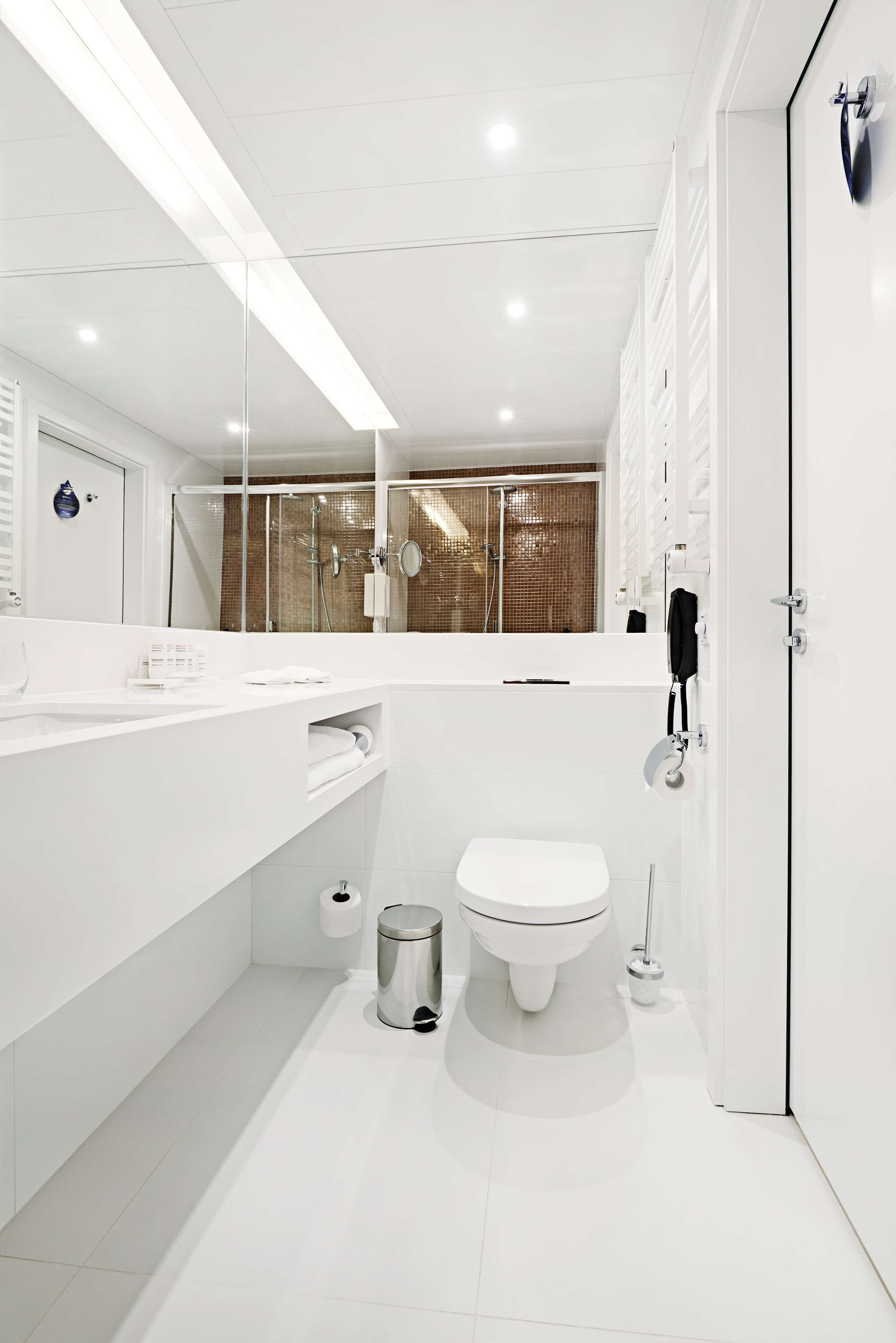 Casa de banho moderna com lavatório branco, sanita e zona de duche.