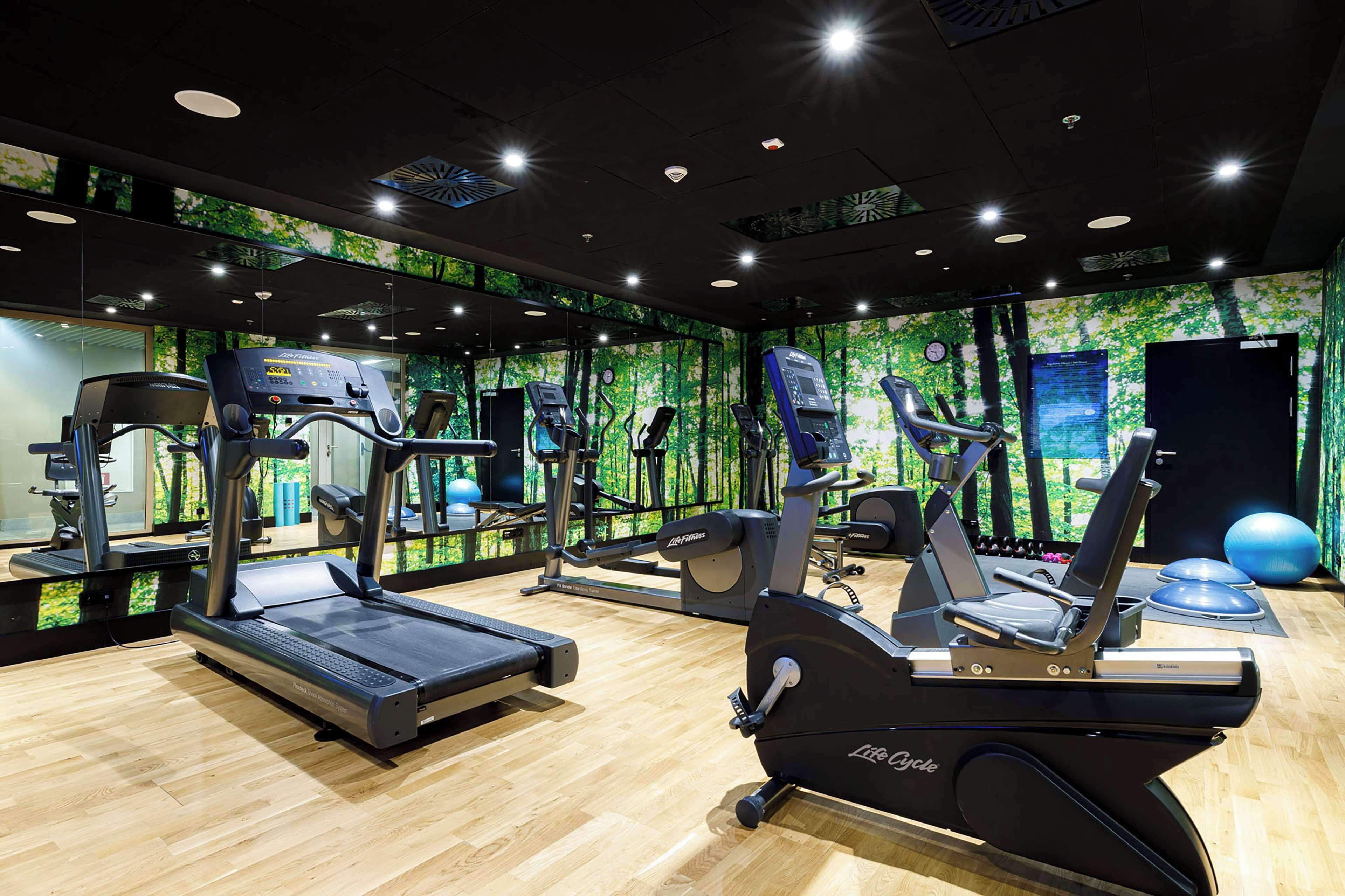 A gym with treadmills, elliptical machines, and exercise balls.