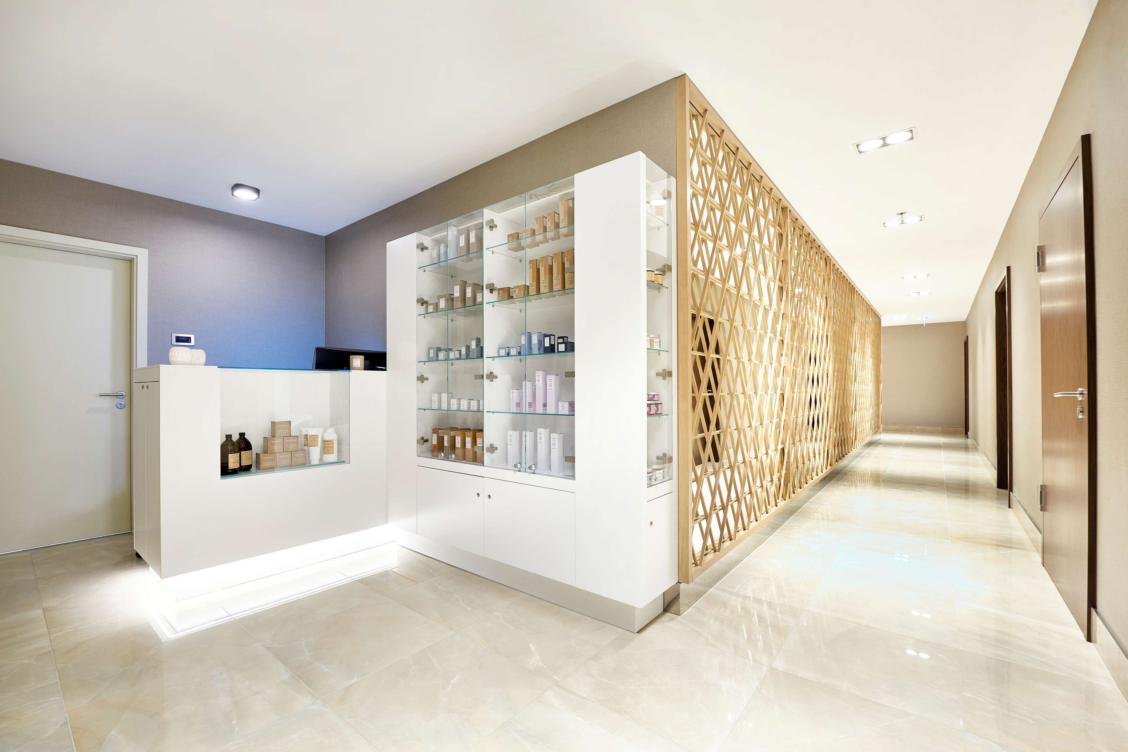 A modern hotel lobby with a reception desk, glass display cases, and a wooden decorative wall.
