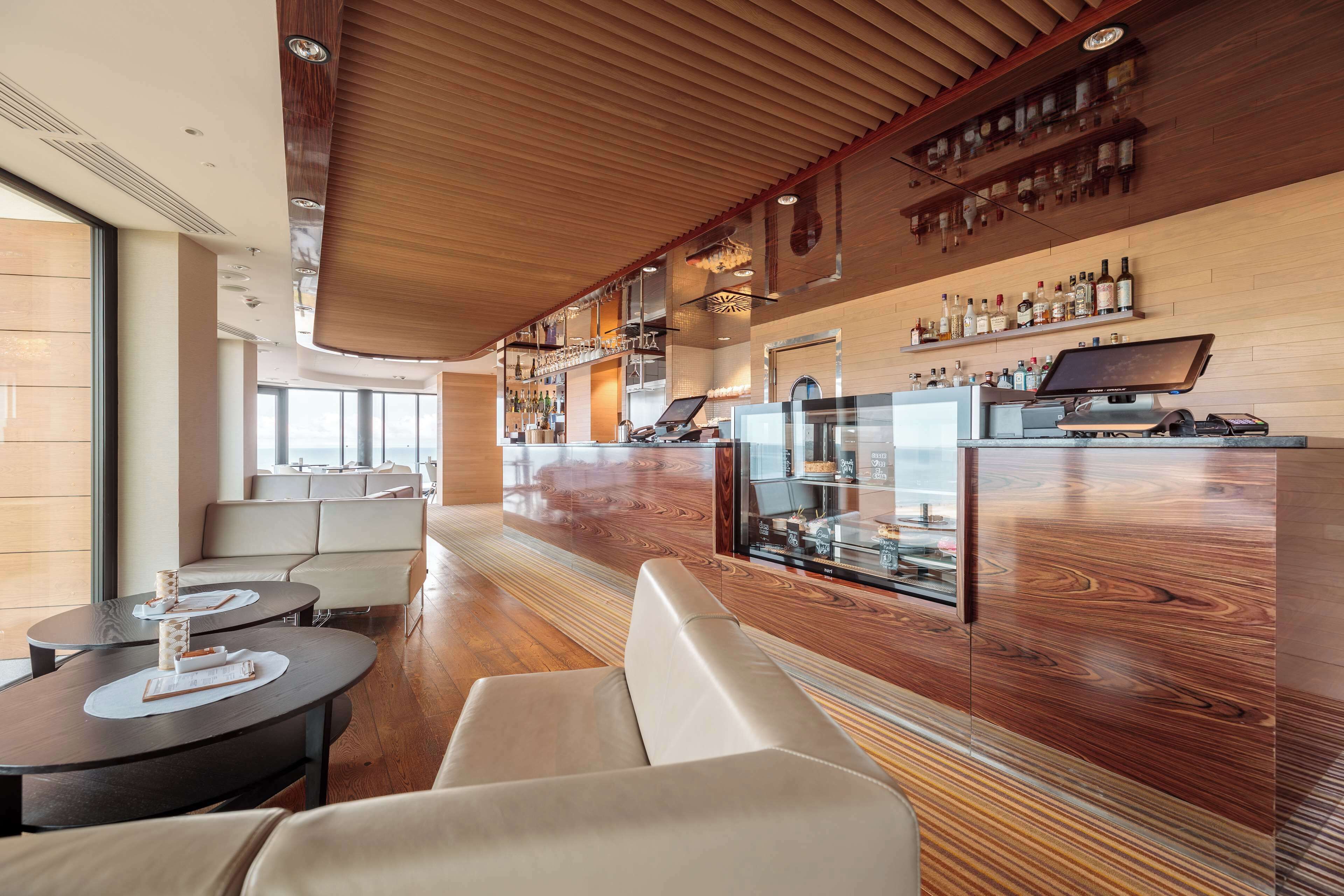 A modern bar area with wooden accents, seating, and a display case.