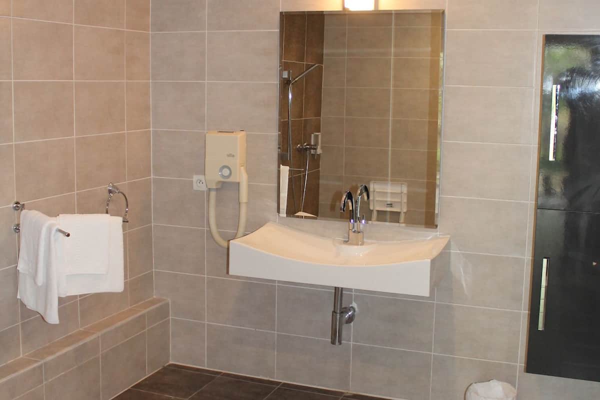 Een badkamer met een wastafel, spiegel en douche.