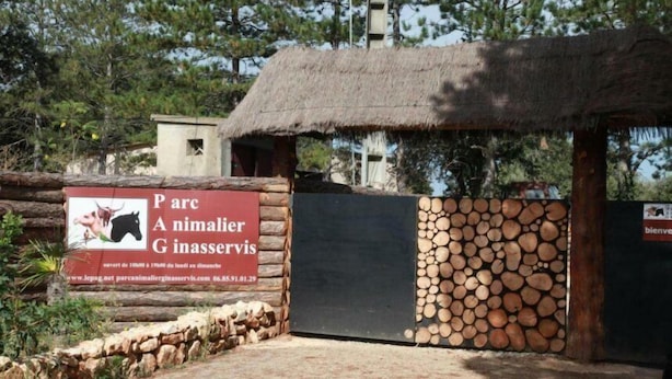 Ein rustikales Gebäude mit einem Reetdach und einem Schild, das einen Park und ein Tierheim bewirbt.