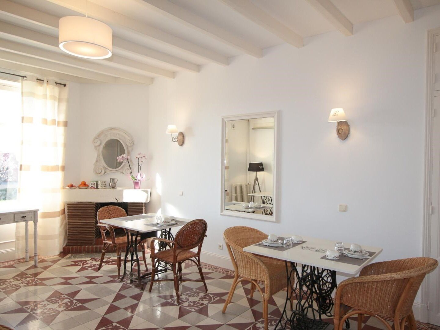 A dining area with a checkered floor, wicker chairs, a white table, and a mirror on the wall.