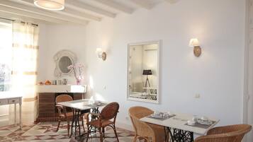 A dining area with a checkered floor, wicker chairs, a white table, and a mirror on the wall.
