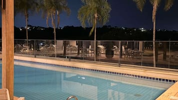 Una piscina al aire libre, sillones reclinables de piscina