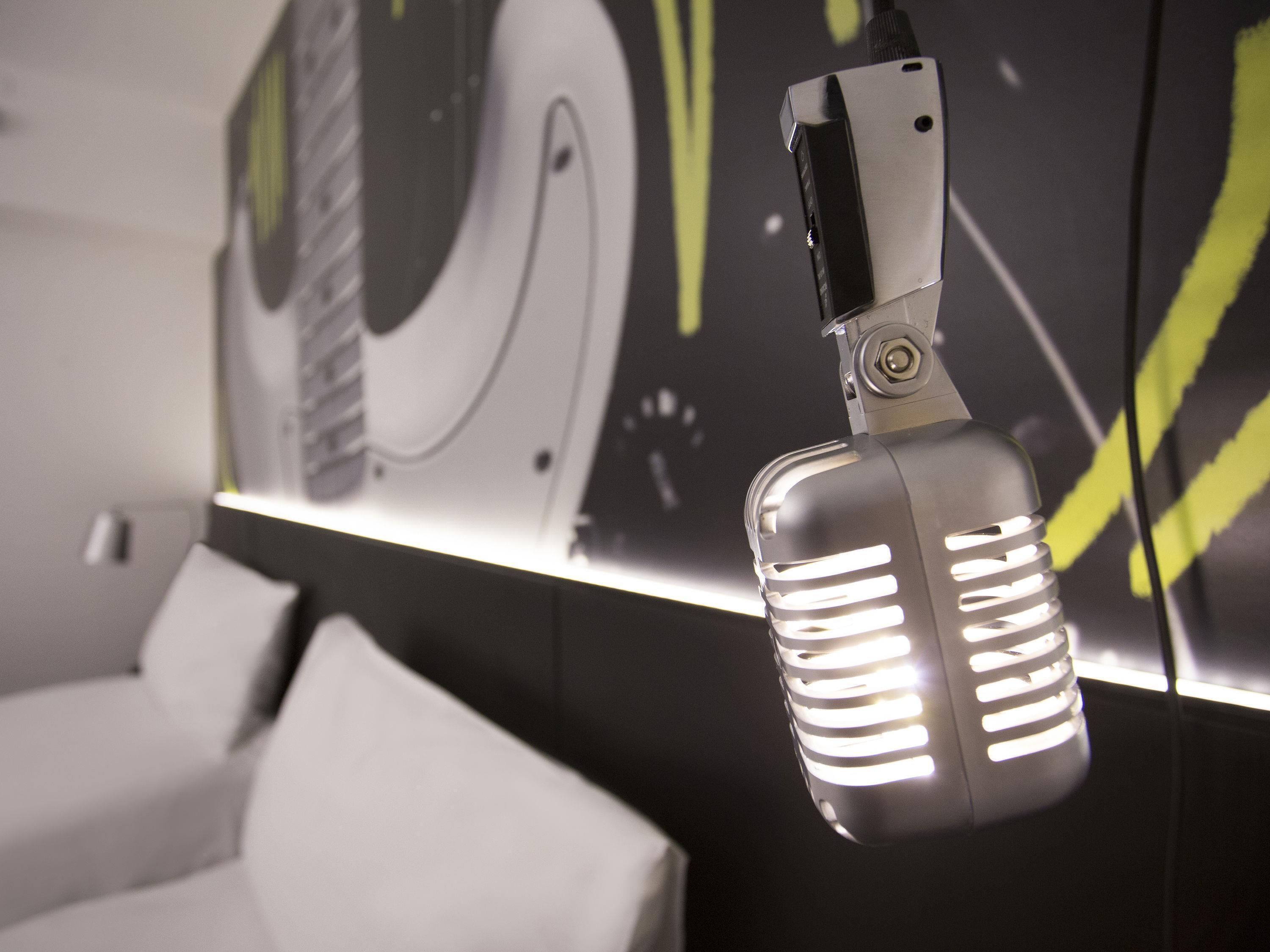 A microphone with a digital display, a white couch, and a wall with abstract art.