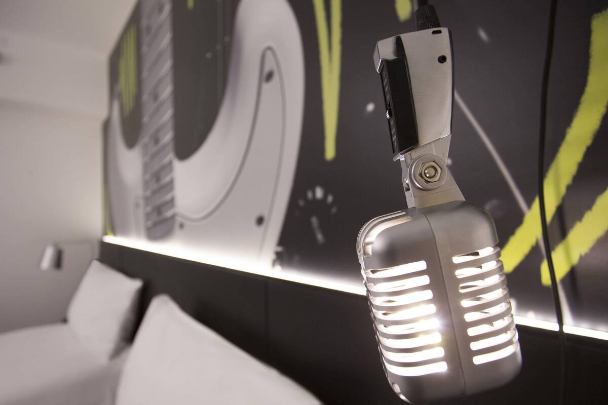 Un microphone doté d’un écran numérique, un canapé blanc et un mur orné d’œuvres d’art abstraites.