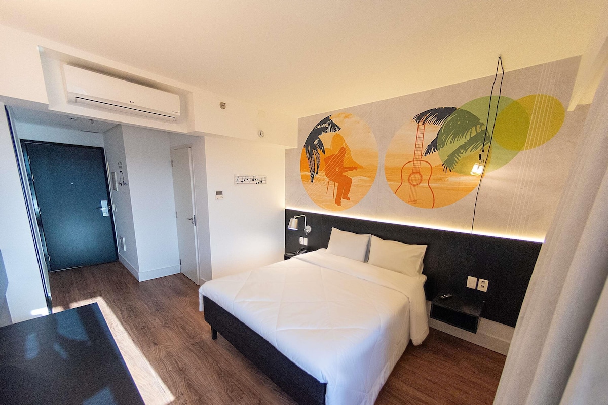 Une chambre d’hôtel avec un lit, un bureau et un mur décoré d’œuvres d’art abstrait.
