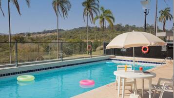 Piscina com vista para a paisagem, uma mesa com cadeiras e um flutuador.