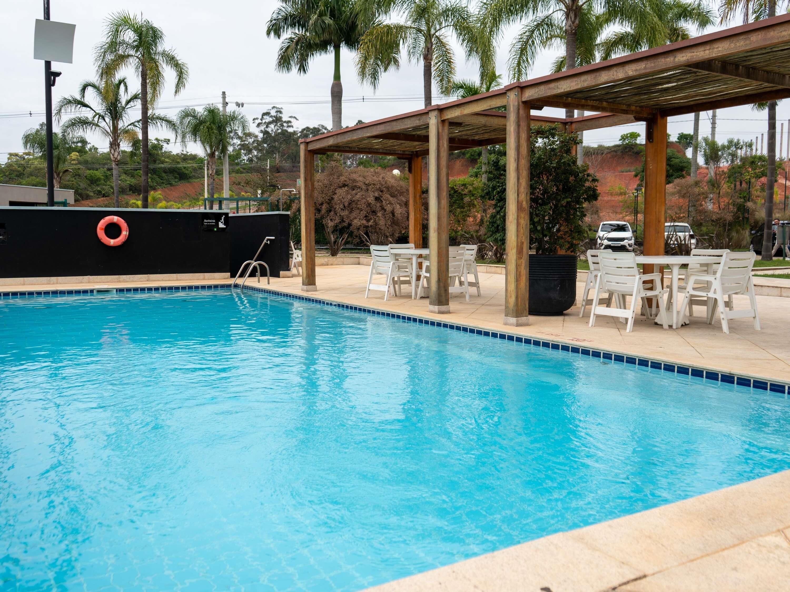 Piscina com área de estar coberta e espreguiçadeiras.