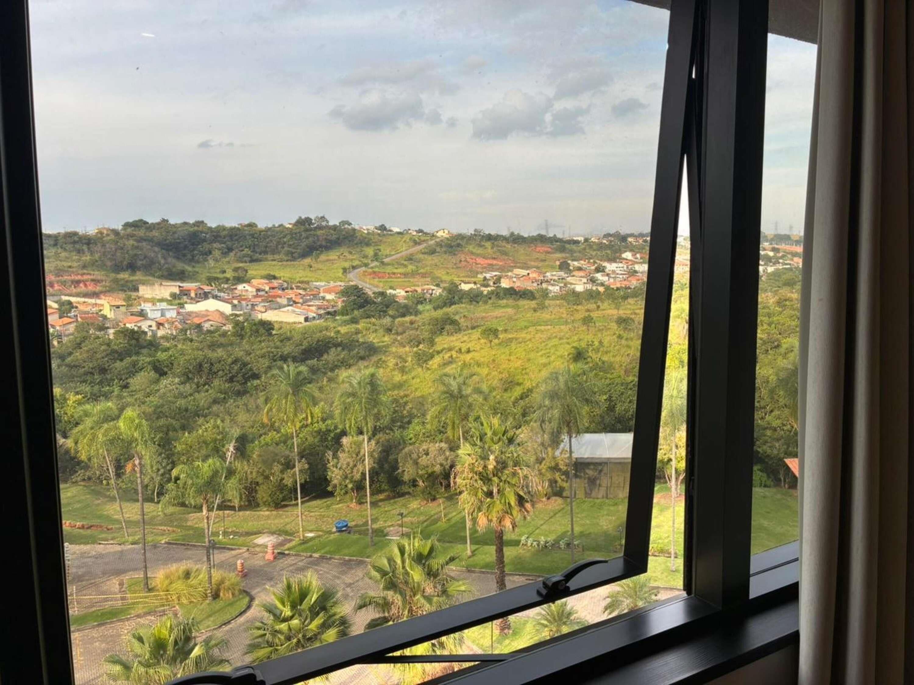 Vista da janela para uma área residencial com casas e vegetação.