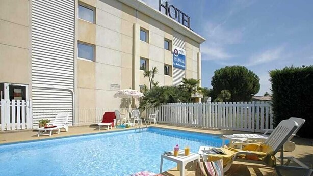 A hotel with a swimming pool, white fences, and lounge chairs. - The Originals City, Hôtel la Belle Étape, Brignoles (Brignoles)