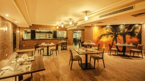 A restaurant with wooden flooring, multiple dining tables, and chairs. There is a kitchen area in the background. - Old Vic Sharm Resort (Sharm El Sheikh)