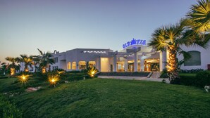A hotel with a modern architectural design, featuring a prominent entrance with steps and a large illuminated sign. - Old Vic Sharm Resort (Sharm El Sheikh)