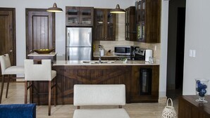 Une cuisine moderne avec des meubles en bois foncé, des appareils électroménagers en acier inoxydable et un îlot central doté de tabourets de bar.