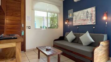 A living room with a wooden table, a sofa, a ceiling fan, and a wall-mounted air conditioner.