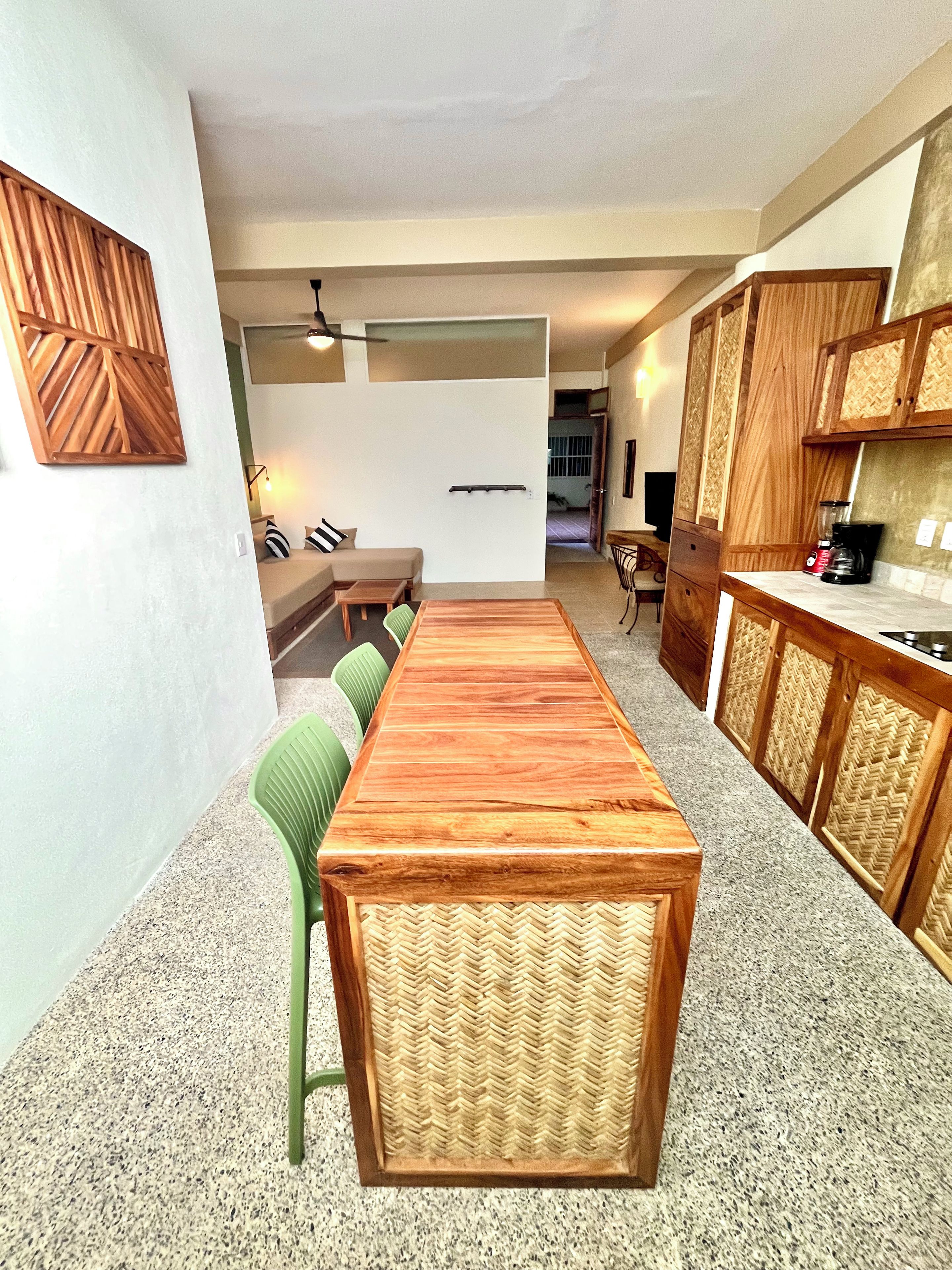 Una cocina moderna con armarios de madera, una mesa de comedor y un área de estar con sofá y sillas.