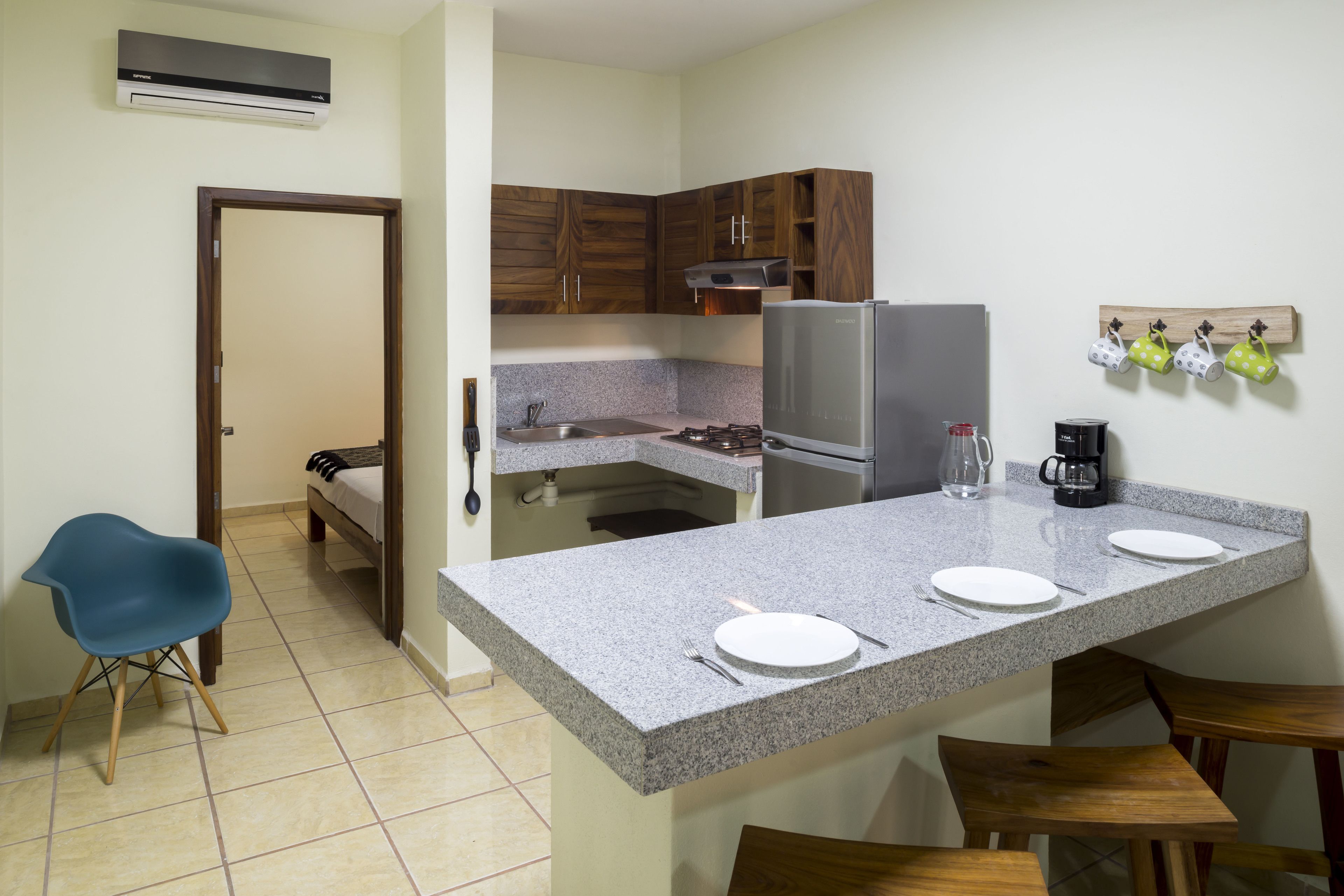 A compact kitchen with a granite countertop, a refrigerator, and wooden cabinets.