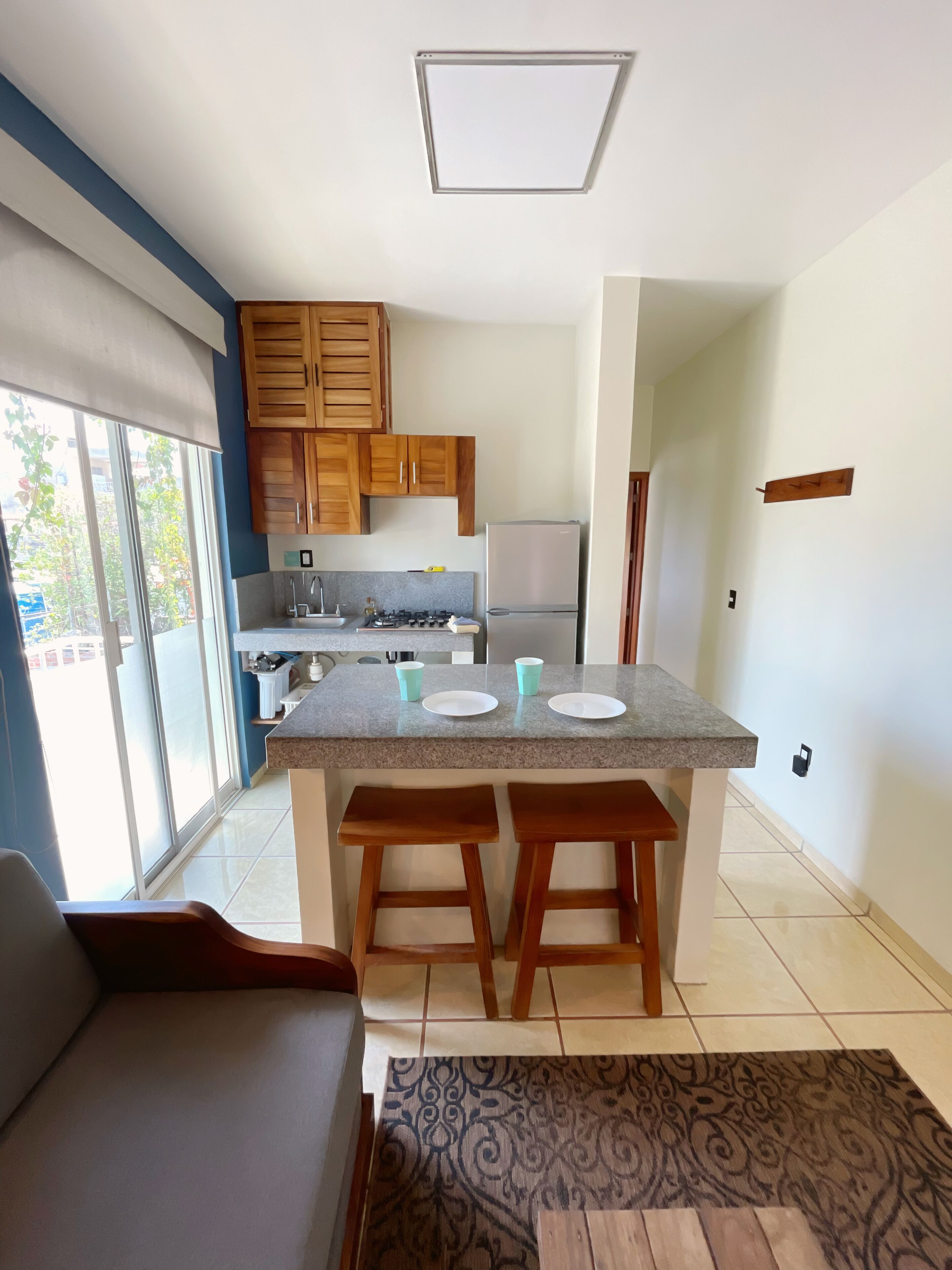 A modern kitchen with wooden cabinets, a granite countertop, and a built-in refrigerator.