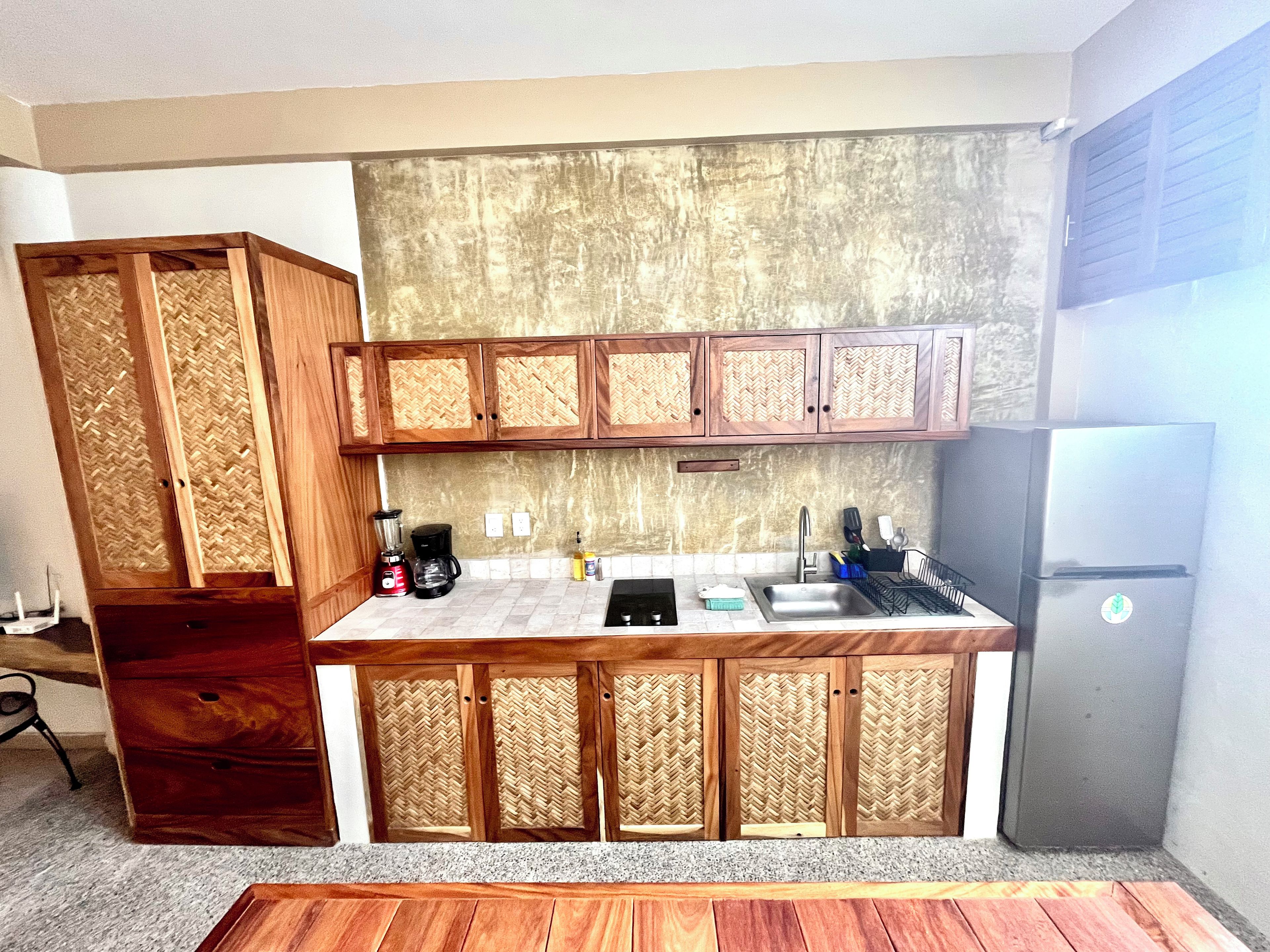 A compact kitchen with wooden cabinets, a built-in sink, and a refrigerator.