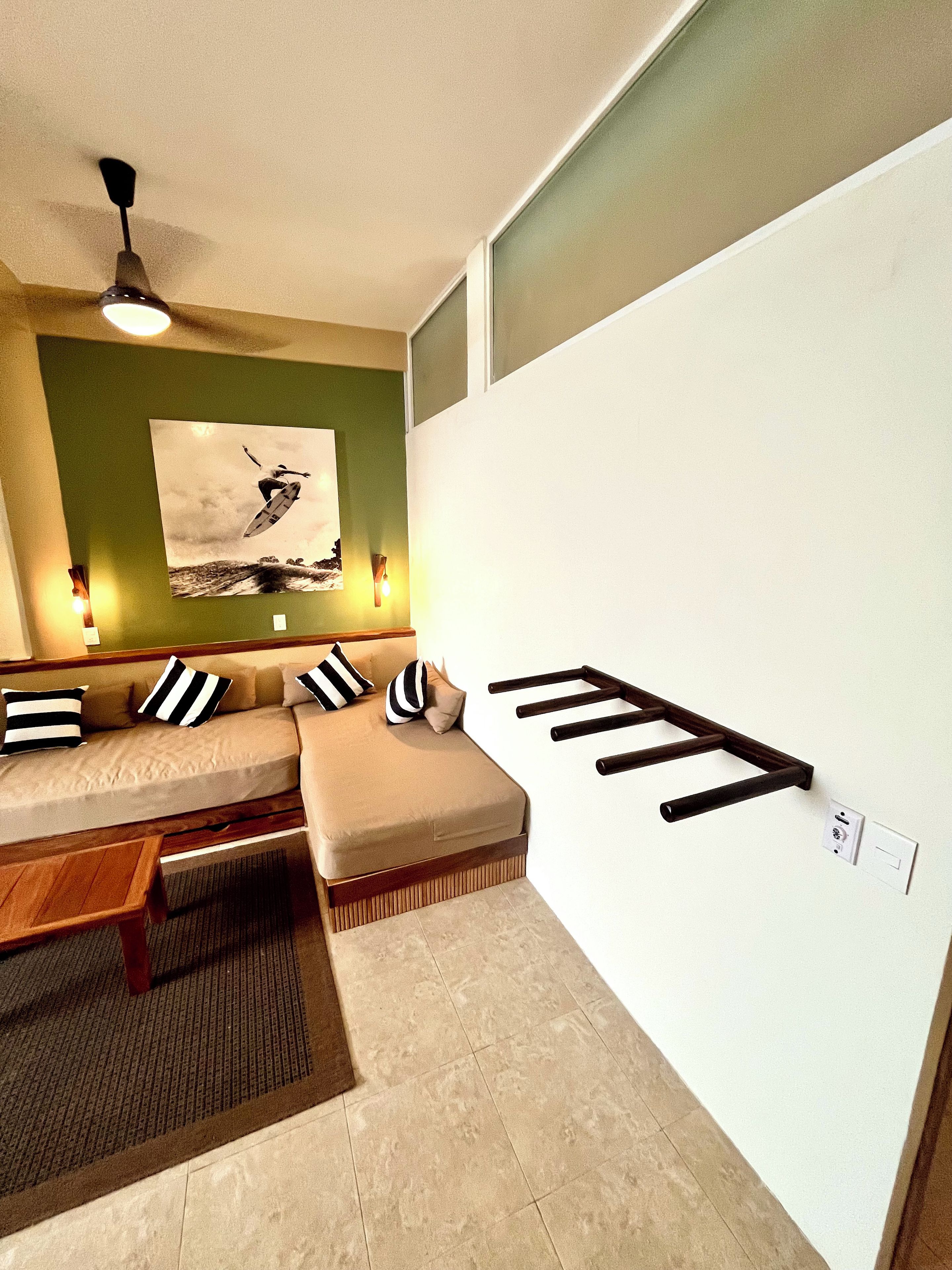 Una sala de estar moderna con un sofá modular, una mesa de centro de madera y una escalera fijada a la pared.