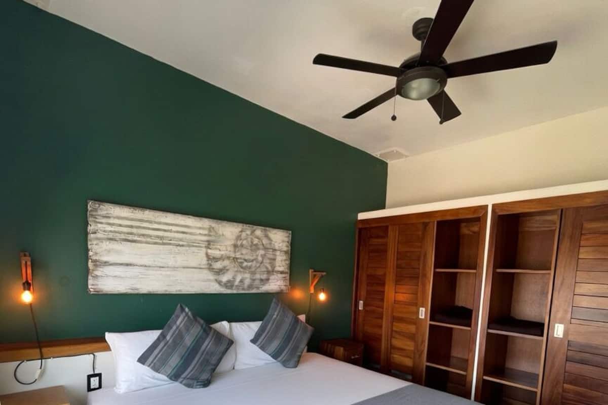 A bedroom with a bed, a ceiling fan, a wardrobe, and a nightstand.