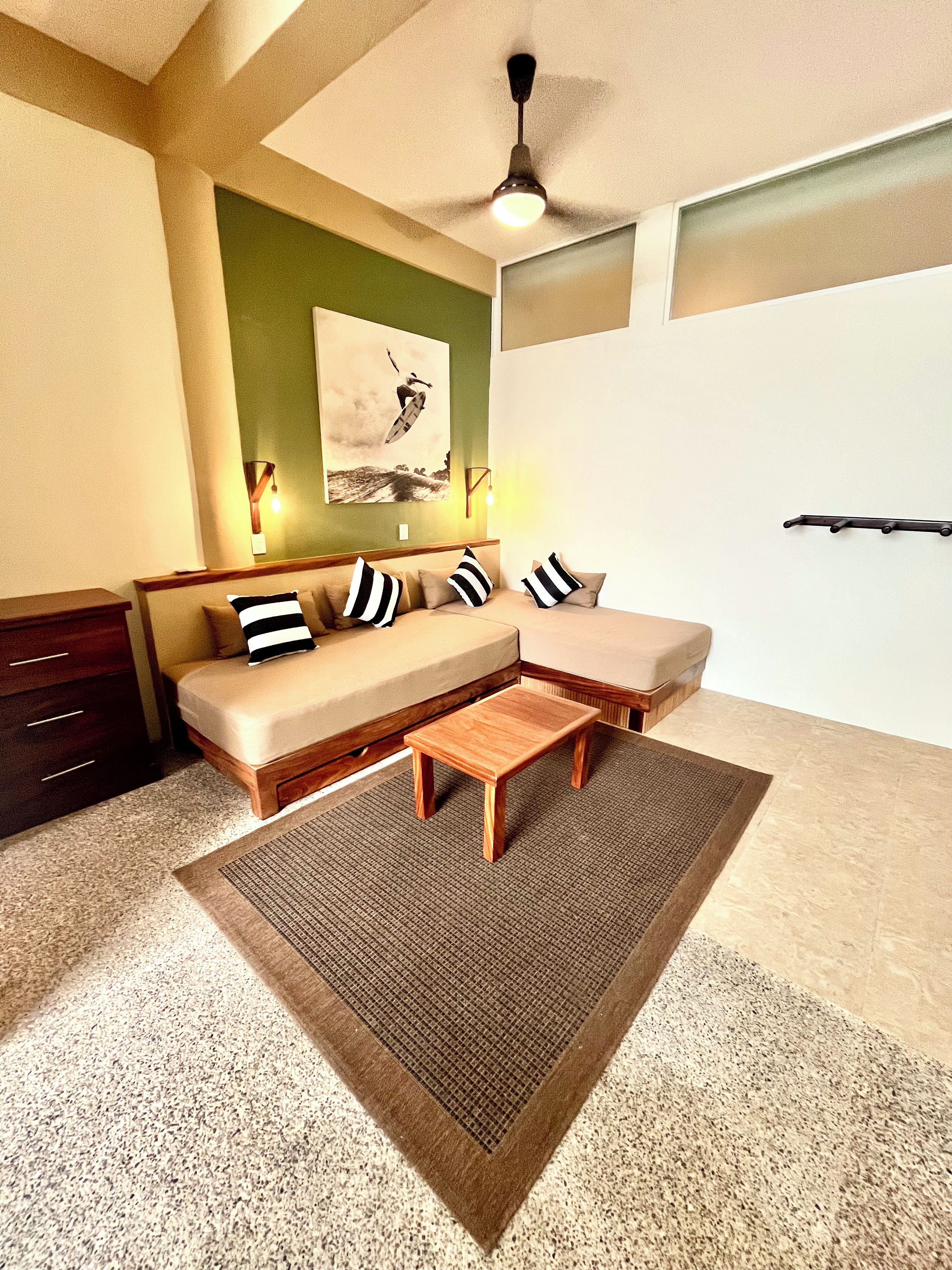Una sala de estar moderna con un sofá modular, una pequeña mesa de centro de madera y un ventilador de techo.