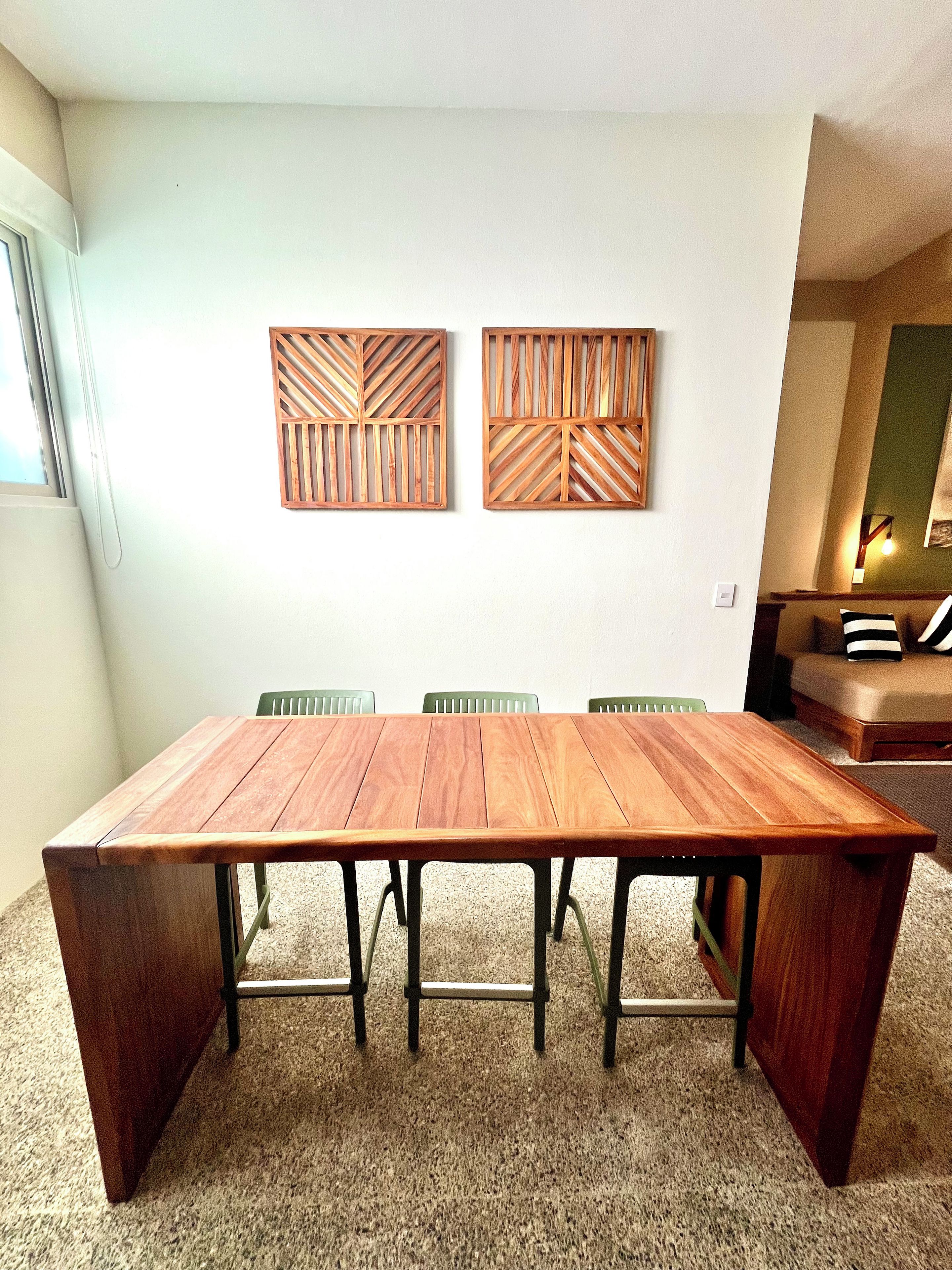 Ein Essbereich mit Holztisch und -stühlen, einer Couch und zwei an der Wand befestigten Holzpaneelen.