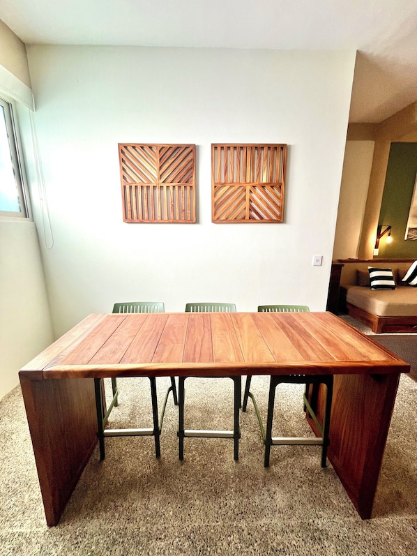 A dining area with a wooden table and chairs, a sofa, and two wall-mounted wooden panels.