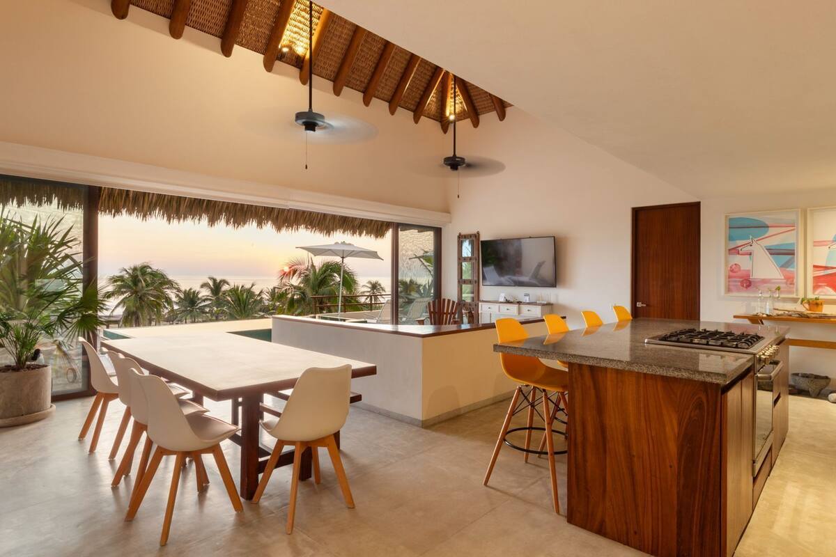Una cocina moderna con una isla grande, comedor y vista al océano.