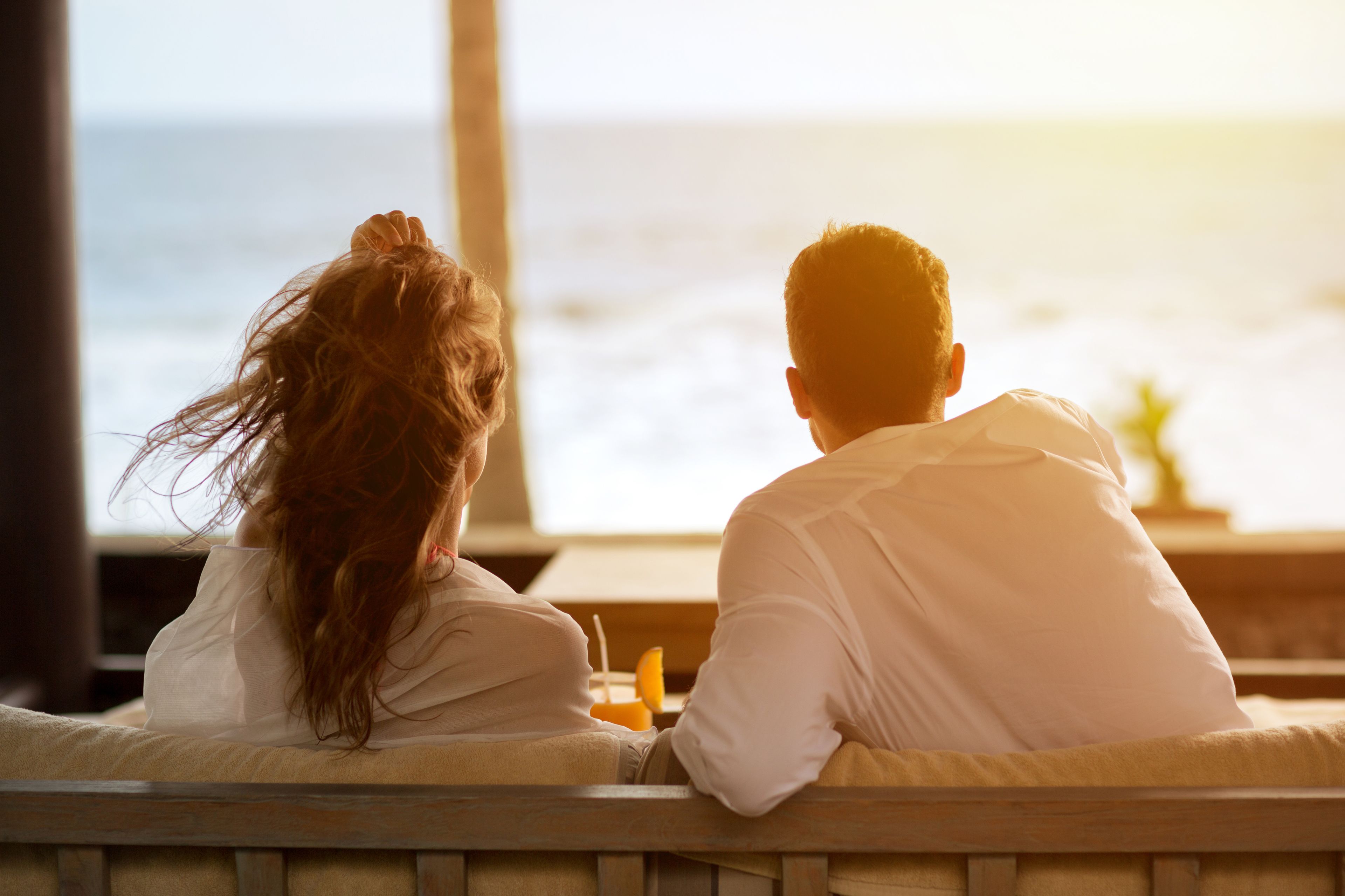 A couple sitting by a window overlooking the ocean.