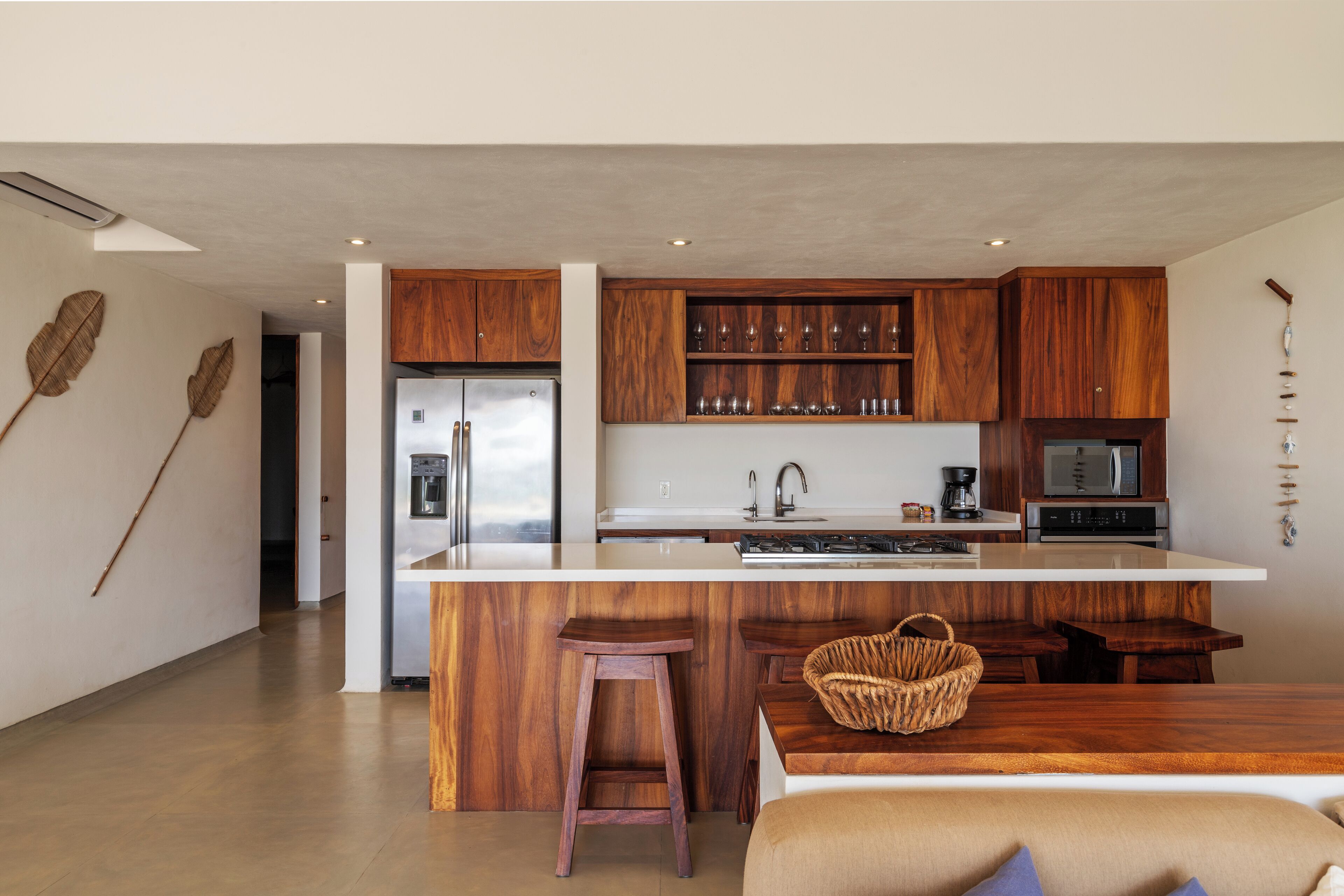 Une cuisine moderne avec des meubles en bois, un îlot central et des tabourets de bar.