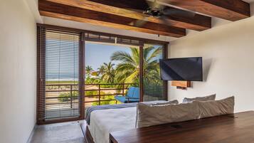 A bedroom with a bed, a TV, and a view of the beach.