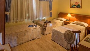 A hotel room with two beds, wooden flooring, a ceiling fan, and a painting on the wall. - Hotel Sky (Gramado)